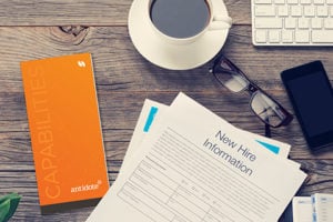 New hire sheet on top of a desk next to a journal and cup of coffee